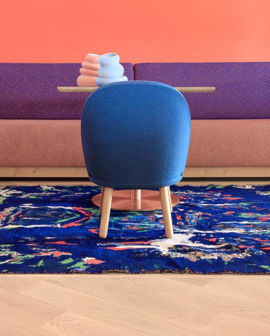 Tisch mit blauem Stuhl und buntem Teppich