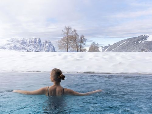 Eine Frau schwimmt im Außenpool im Winter